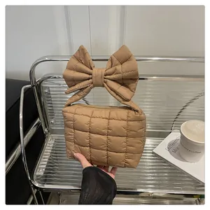 Detail of the oversized quilted bow handle on a khaki nylon handbag with zip closure