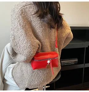 Detail of red crossbody square bag featuring silver zipper and unique robot charm
