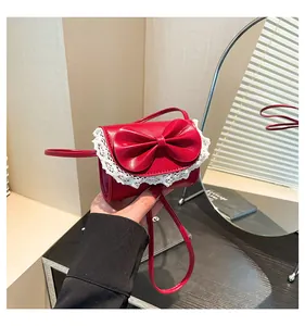 Detailed view of red mini crossbody bag with leather bow decoration and white lace trim