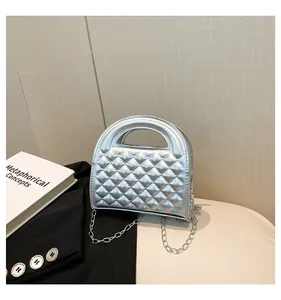 Close-up of silver quilted handbag featuring metallic finish and chain strap on light background