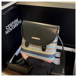 Close-up of rainbow straw bucket bag with black leather flap and gold hardware detail