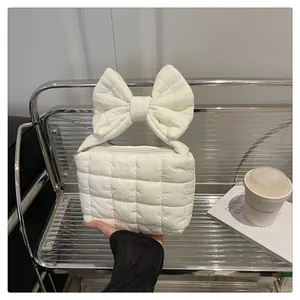 Close-up of white quilted handbag with a large decorative bow and soft nylon texture