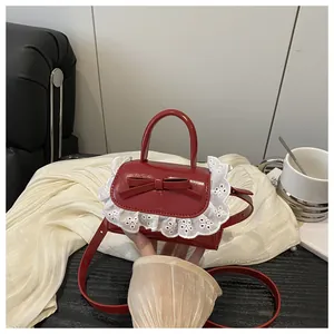 Macro shot of red patent leather mini bag with bow accent and white lace trim