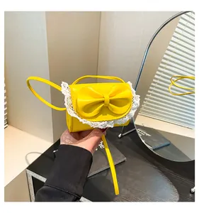 Close-up of bright yellow mini handbag featuring a large bow and white lace trimming