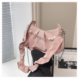 Detail of pink pleated crescent bag with pearl chain and metallic heart charm accents