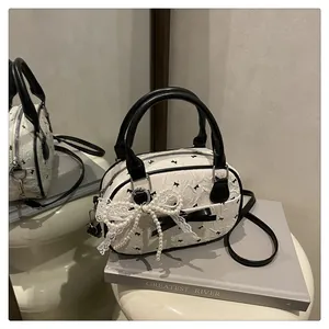 Close-up of white bowling bag with black bow patterns, lace details and pearl tassels