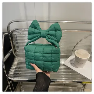 Detail of green quilted handbag featuring oversized bow handle and secure zipper closure