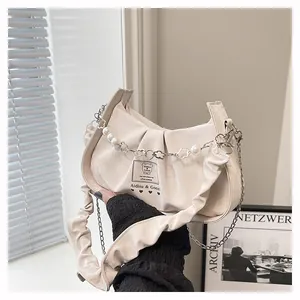 Detail of cream pleated baguette bag with pearl chain and artistic lettering design