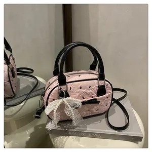 Close-up of pink Boston bag featuring black butterfly patterns and pearl lace charm