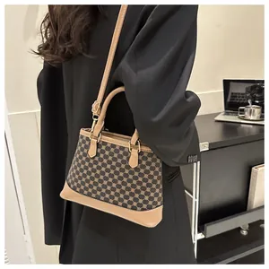 Detail of vintage patterned crossbody bag with leather handles and gold hardware accents