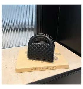 Detail of black quilted shoulder bag with silver chain strap on a designer book