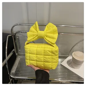 Macro shot of bright yellow quilted nylon handbag with unique oversized bow handle detail