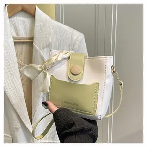 Close-up of cream and green bucket bag with wood-grain buckle and silk scarf detail