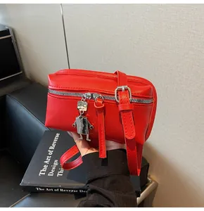 Detail of red square crossbody bag with metallic robot pendant and adjustable strap