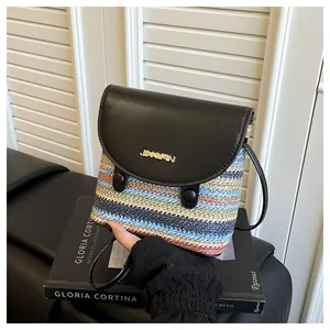 Detail of colorful woven straw bucket bag featuring black leather flap and gold logo