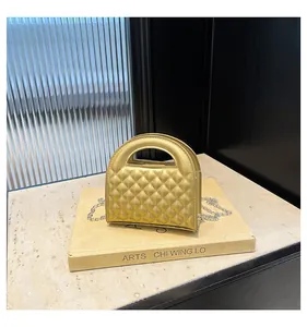 Close-up of golden quilted handbag featuring a top handle cutout and silver chain strap