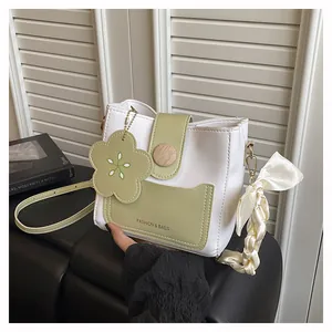 Detail view of contrast color bucket bag with wooden buckle and silk scarf decoration
