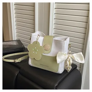 Detail of green and white bucket bag with floral charm, wooden buckle and silk ribbon