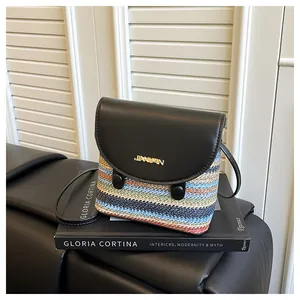 Detail of colorful woven straw bucket bag with black leather flap and gold logo