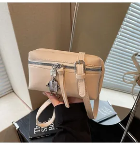 Detail of cream square crossbody bag with a cute robot charm and metallic silver zipper