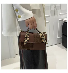 Detail of crossbody bag featuring leopard print panel and silk scarf wrapped handle