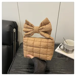 Detail shot of khaki quilted handbag with decorative bow handle and top zipper closure