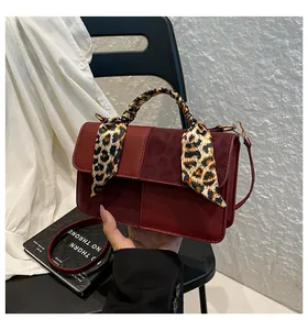 Detail of dark red crossbody bag with leopard print scarf and golden metal buckle