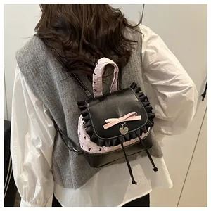 Detail von rosa Rüschenverzierung und Herzanhänger an einem süßen zweifarbigen Rucksack