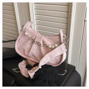 Detailed shot of pink pleated baguette bag with pearl flower chain and brand label