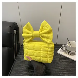 Quilted yellow handbag with oversized bow handle and top zipper detail macro
