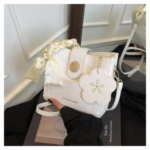 Detailed shot of white bucket bag with silk scarf handle and floral charm pendant