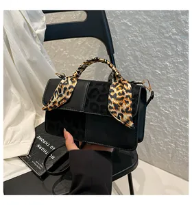 Detail of crossbody bag with leopard print texture and silk scarf wrapped on handle