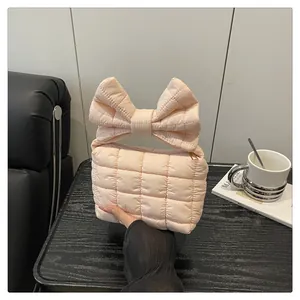 Detail shot of the pale pink quilted handbag featuring a large puffy bow handle design