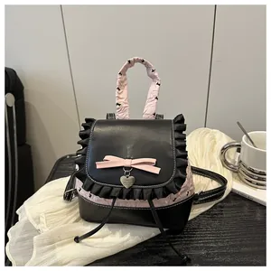 Detail von Spitzenbesatz und rosa Schleife am Rucksack mit einem Herz-Metallanhänger