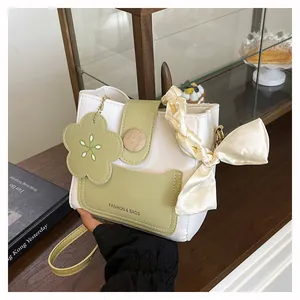 Detail of water bucket bag with wooden button closure, floral charm and silk scarf decoration