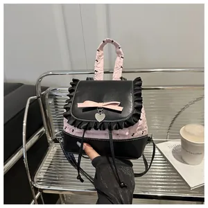 Detail eines Mini-Rucksacks mit rosa Rüschen, schwarzer Spitze und silbernem Herzanhänger