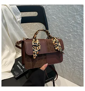 Detail of crossbody bag with leopard print flap and scarf wrapped around the handle