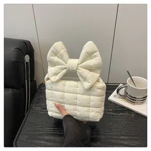 Detail of a creamy quilted handbag featuring a large bow and soft cotton texture