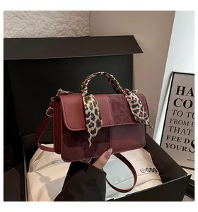 Detail of burgundy patchwork crossbody bag with leopard print scarf and shoulder strap