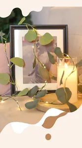 Detail of warm yellow LED fairy lights woven through realistic green eucalyptus leaves