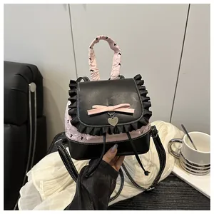 Detail einer rosa Schleife und Herzanhänger mit Rüschen auf Lederrucksack