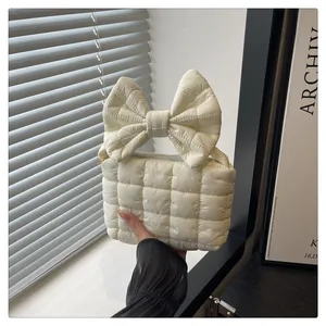 Detail of white quilted handbag featuring a large puffy bow handle and modern design
