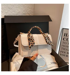 Detail of cream crossbody bag with leopard print silk scarf wrapped around the top handle