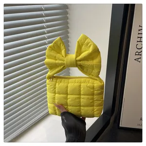 Close-up of bright yellow quilted nylon handbag featuring a large bow handle design