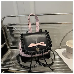 Detailansicht eines rosa Spitzenrucksacks mit Herzanhänger, Schleife und Trägern