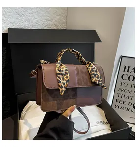 Detailed macro shot of vintage brown leopard print handbag with golden hardware and silk scarf