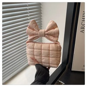 Close-up of pink quilted handbag with oversized bow handle and golden zipper detail
