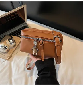 Detailed close-up of brown leather bag featuring a silver metal zipper and robot charm