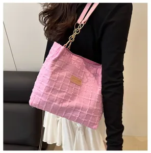 Detail of pink wool tote bag featuring textured fabric and gold metal chain strap connector