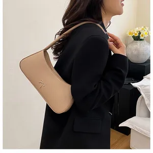 Detail der eleganten beigen PU-Schultertasche mit einer stilvollen hellgoldenen Metallschleife
